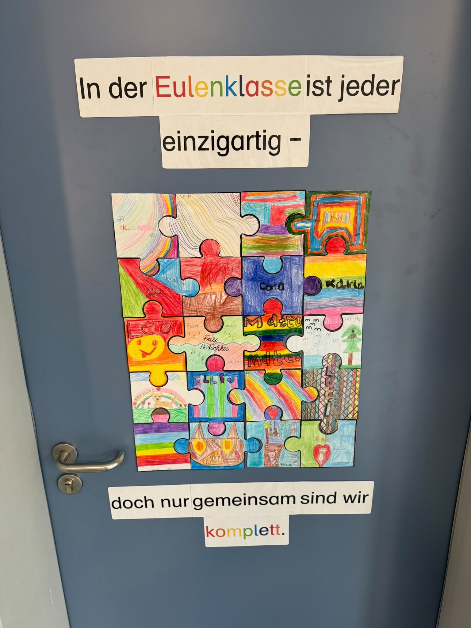 Es ist die Klassenzimmertür der Eulenklasse zu sehen, die von einem Kunstprojekt geschmückt ist.